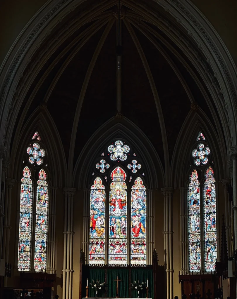 Stained glass windows above the altar inside a Catholic cathedral.