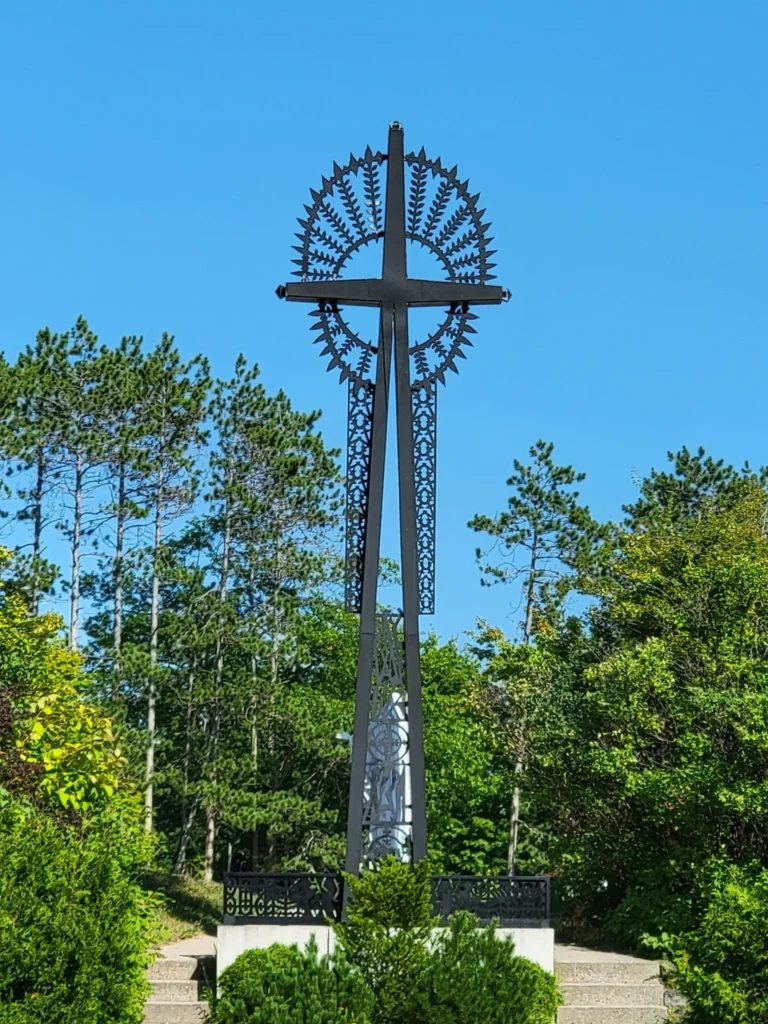 Large cross standing in a prayer garden at a Catholic pilgrimage site.